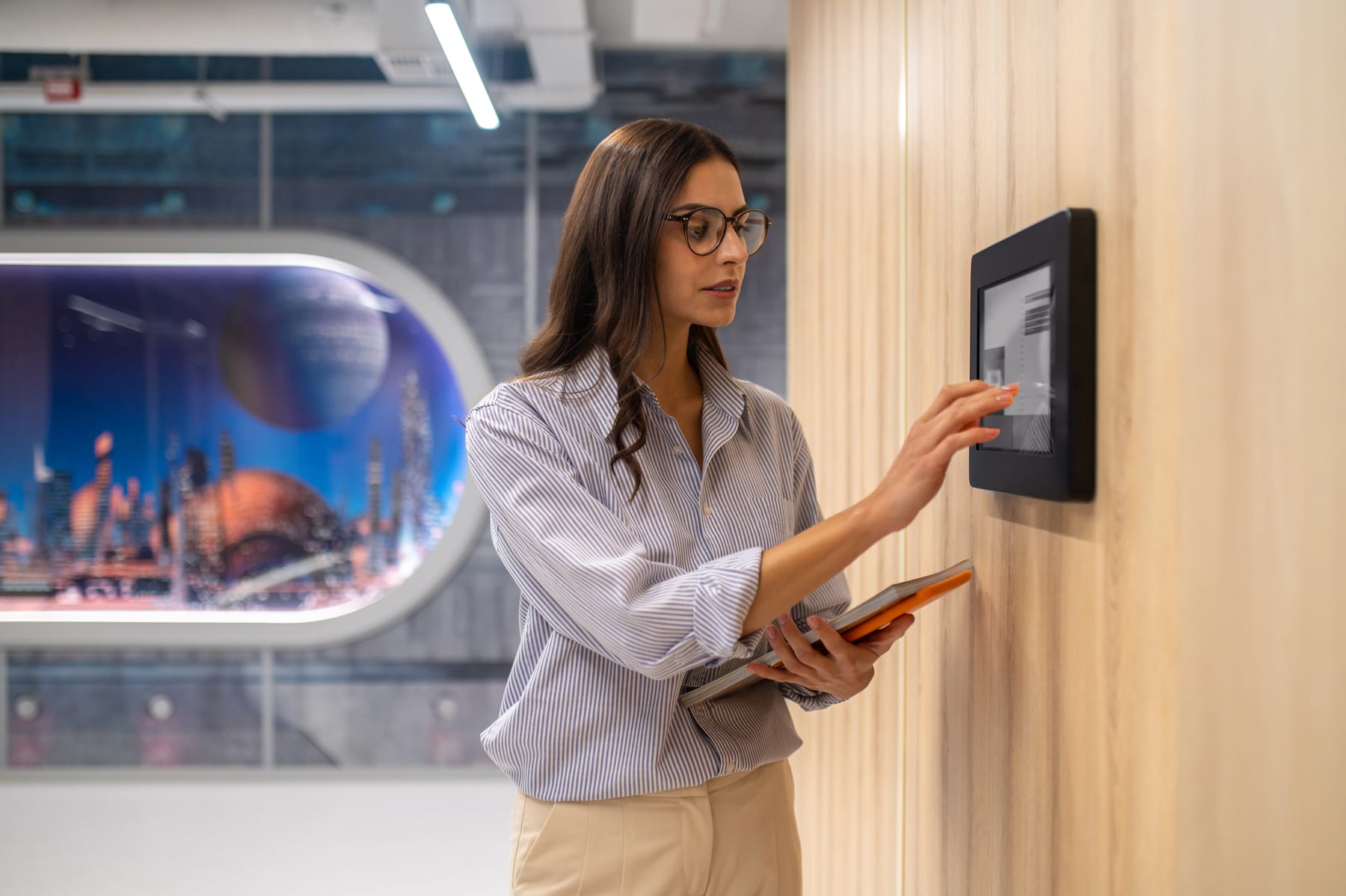 Woman using a wall-mounted cloud access-control panel in a modern office